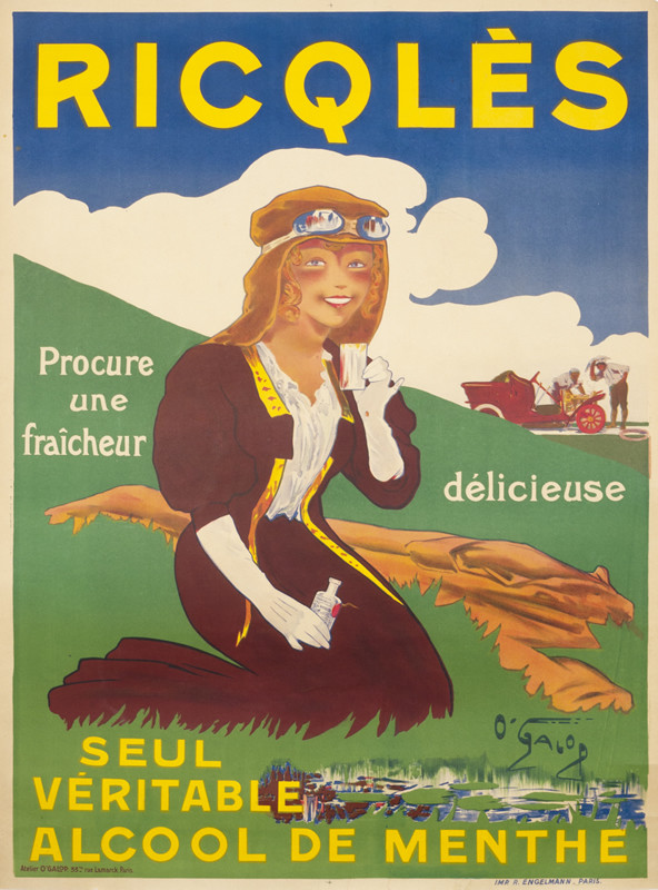 woman in goggles and shawl  takes break from driving and sits on grass with bottle; green, brown, yellow