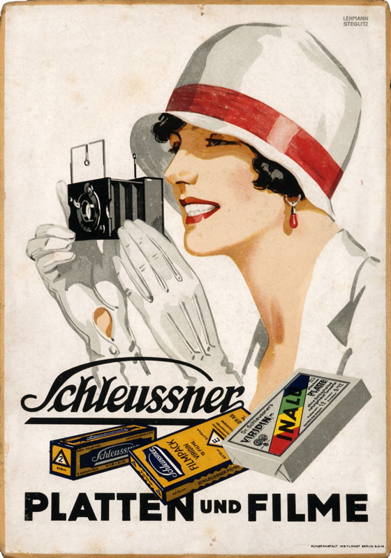 Woman in hat and gloves takes picture with camera; red, white, yellow