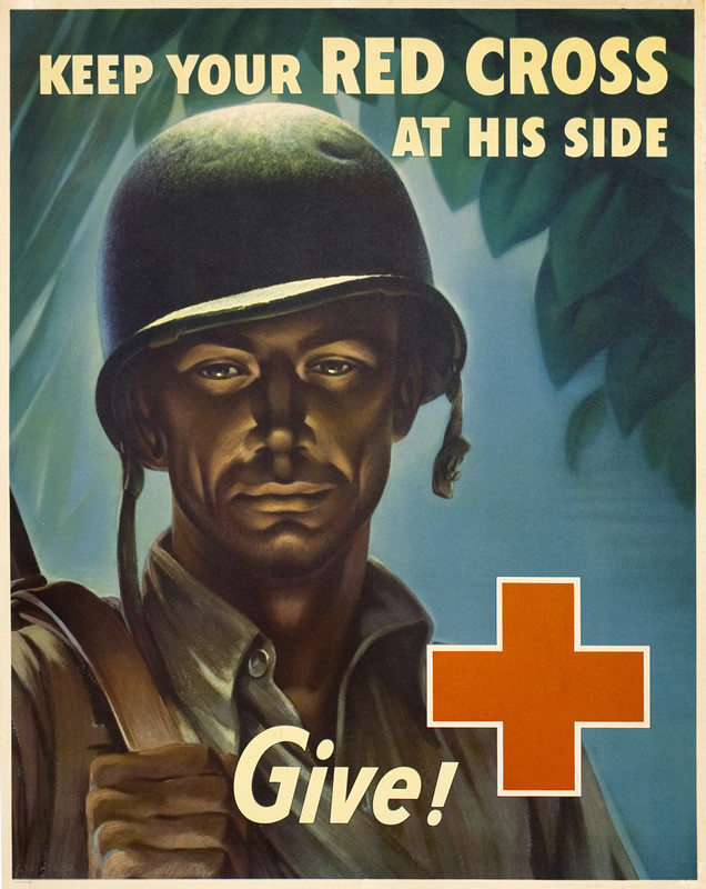 Close up of solider wearing helmet, tropical greenery behind, red cross; blue, brown, green