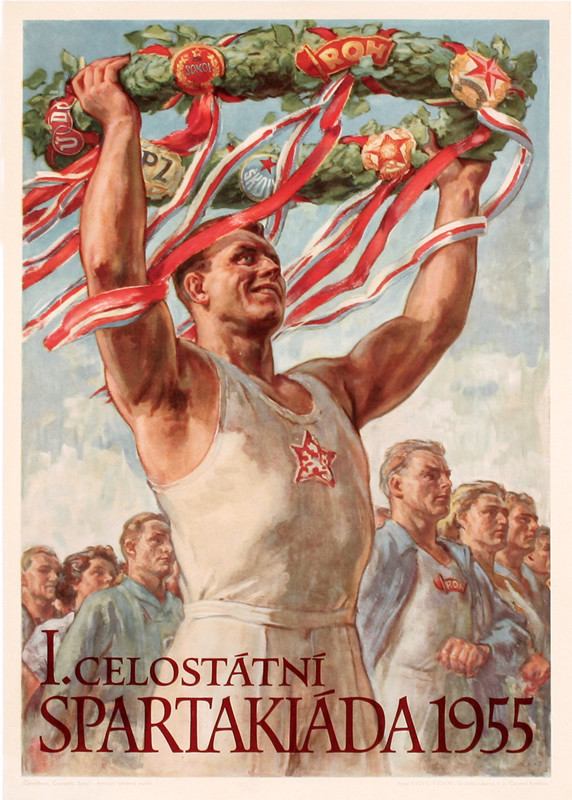 Sports victor holds wreath with ribbons and badges high above head, sportsmen behind him; blue, green, white